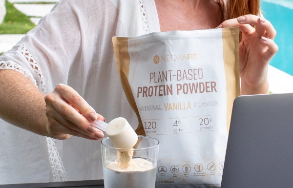 A woman mixing Plant-Based Protein Powder into a glass cup.